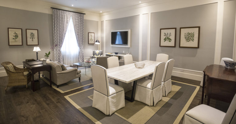 Park Suite interior with dining table and chairs for six, desk, chair, loveseat, coffee table, TV and window at Hotel del Parque in Guayaquil, Ecuador