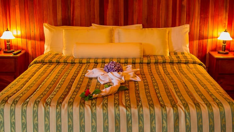 A room at the Hotel Heliconia in Costa Rica's Monteverde region offers home-style comfort, a large bed, fresh towels, and flowers