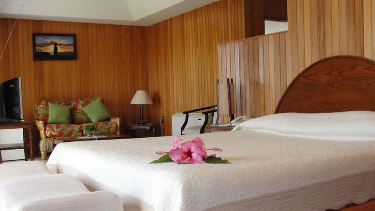 deluxe room with a king bed, wooden walls and flowers on the comforter at hotel iorana easter island in chile