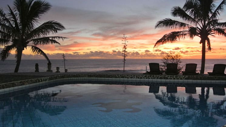 sunset at the pool overlooking the ocean with vibrant clouds and colors in the distance at hotel iorana easter island in chile