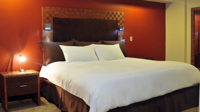 The large bed inside the King Suite with a nightstand and a reading light at the four-star Hotel Presidente, in downtown San José, Costa Rica