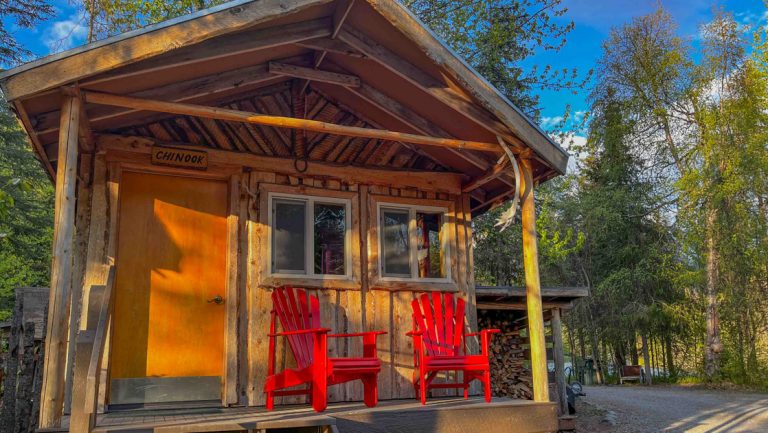 Guest log cabin at Kenai Riverside Lodge fishing & nature retreat in Alaska, with red Adirondack chairs on front porch.