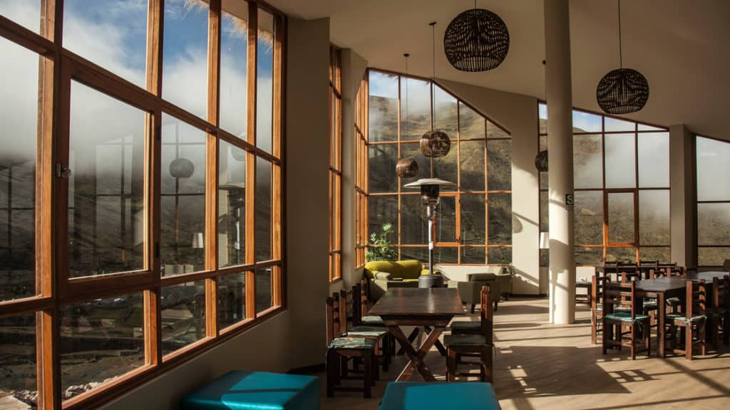 The common area at the Mountain Lodges of Peru in the Lares Region for trekkers, with tables, chairs, and well-positioned windows to maximize the view.