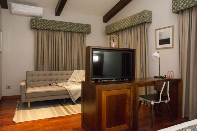 A guest room with a television, couch, king-sized bed and drapes at the family-owned Los Brezos Hotel, near the Baru Volcano in Panama