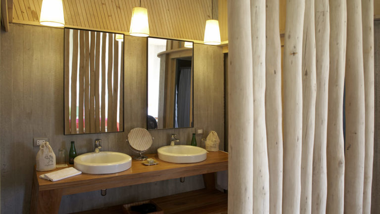 Two sinks and a mirror on the vanity inside a bathroom at Posada de Mike Rapu, a luxury eco hotel in a LEED-certified building.