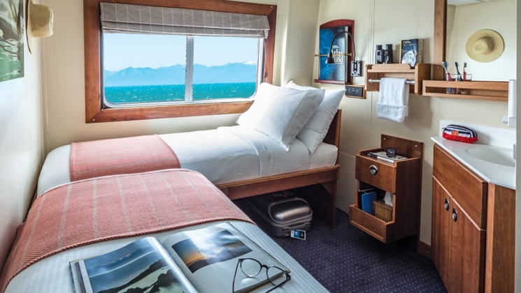 Category 1 Cabin 305 aboard National Geographic Sea Bird small ship, with 2 twin beds, picture window and small sink.