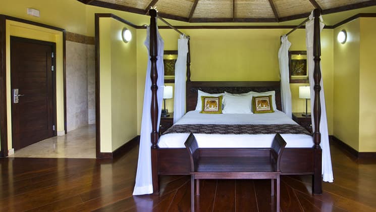 A room with a queen-sized bed, yellow walls, traditional woodwork, a mosquito net at the Nayara Hotel, Spa & Gardens, a luxury boutique hotel in Costa Rica