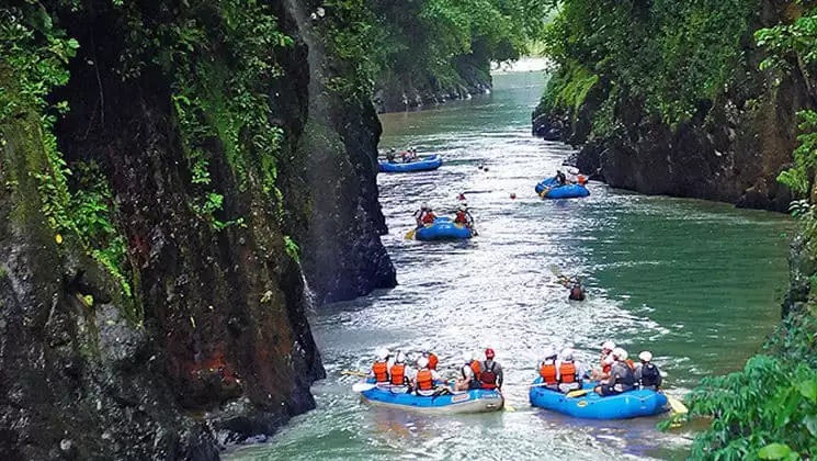 Rafters float down Costa Rica’s Pacuare River between steep cliffs and lush vegetation.