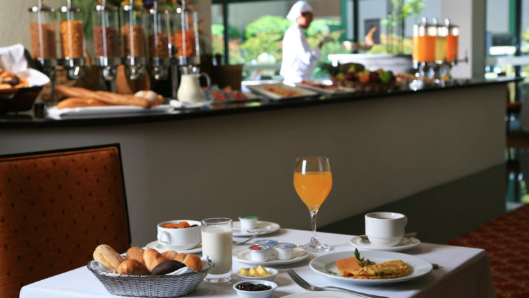 A table is set with fresh orange juice, an omelet, and a basket of bread during the breakfast buffet at Casa Andina Private Collection Miraflores, serving regional ingredients in Peru.