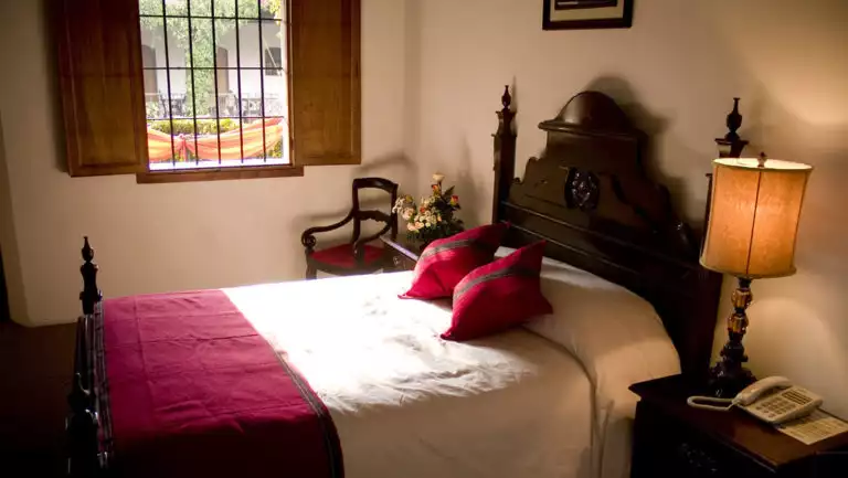 A room with a double bed, decorated in the colonial style of Antigua, inside the historic, renovated Hotel Posada Don Rodrigo