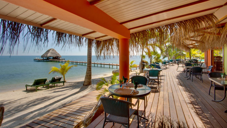 Tables are set for a relaxing oceanfront meal on the deck, next to the beach, at the Inn at Robert's Grove, a boutique hotel ideal after a day exploring Belize's barrier reef or tropical rainforest