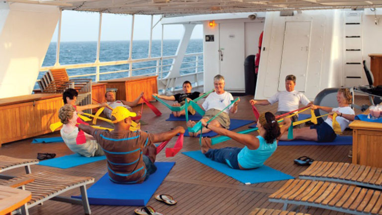 Guests doing morning stretch class on deck of National Geographic Sea Lion small ship.