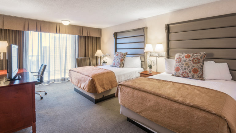 A standard room with two queen-sized beds, a dresser, reading lamps, and nightstand at the Westmark Anchorage, a downtown hotel that was recently renovated