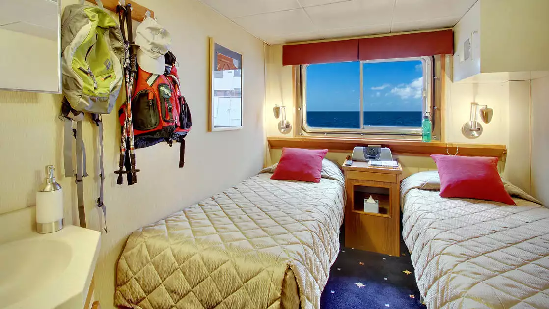 Navigator cabin with twin beds and window aboard Wilderness Discoverer