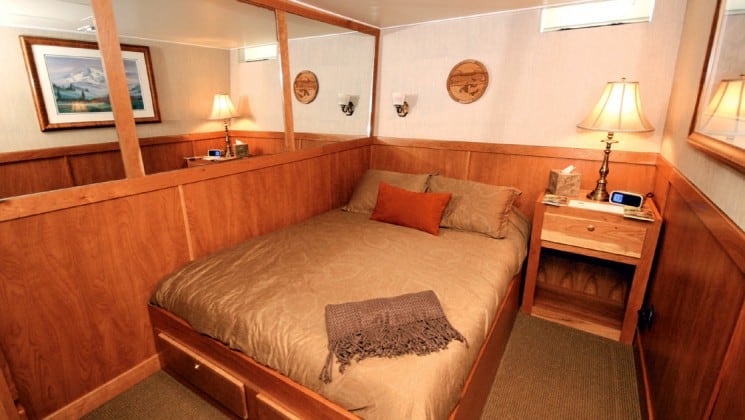 Safari Quest Alaska small ship Navigator stateroom with a large bed, wall mirror and end table