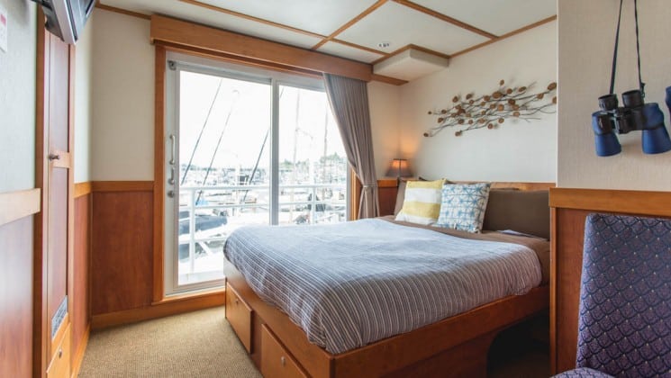 Safari Quest Alaska small ship room with a large bed, decorative metal element above it and a large window behind it