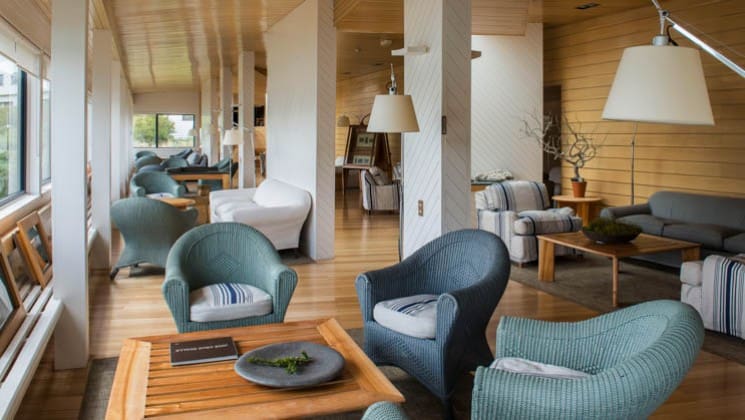 Couches and chairs set around tables near the windows of the common lounge at Explora Torres del Paine Lodge in Chile