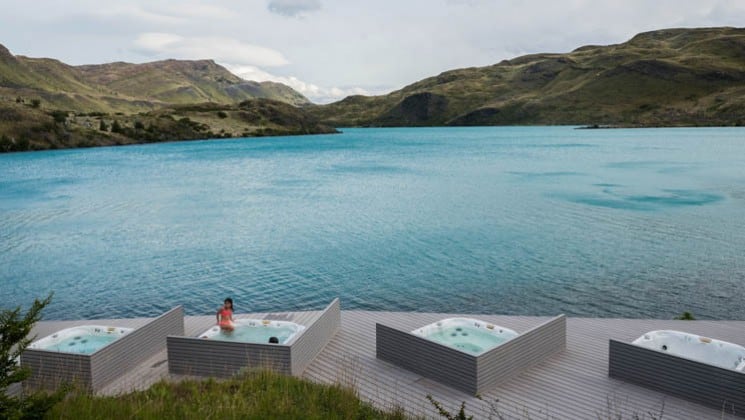 Four outdoor hot tubs placed on a deck with unobstructed views of the lake and mountains at Explora Torres del Paine Lodge in Chile