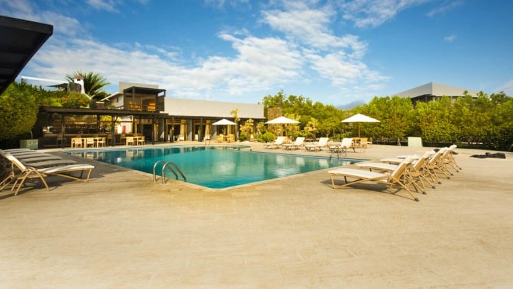 Large outdoor pool surrounded by lounge chairs at Finch Bay Eco Hotel in the Galapagos Islands