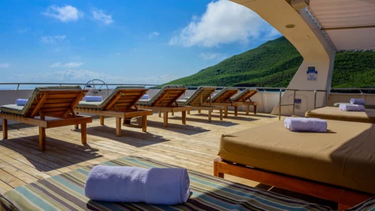 Chaise loungers set up with rolled-up towels on the Sundeck of the Seaman Journey Galapagos yacht.