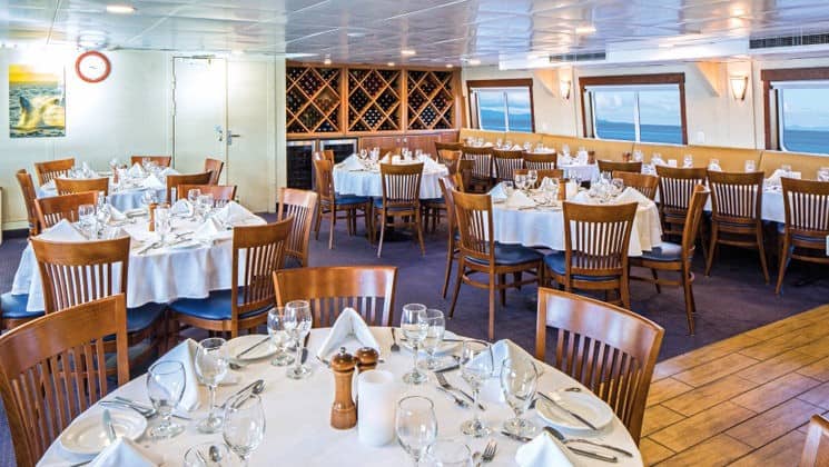 Dining room with window-lined walls aboard National Geographic Sea Bird small ship