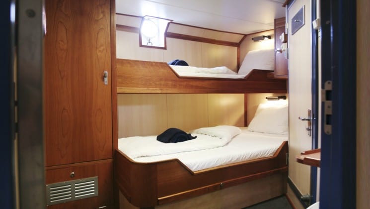 twin beds with a porthole on the wall in the cabin of the Rembrandt van Rijn arctic small ship