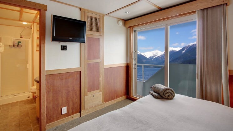 Admiral stateroom aboard the Safari Quest Alaska small ship, with a large bed, flat screen tv and large picture windows