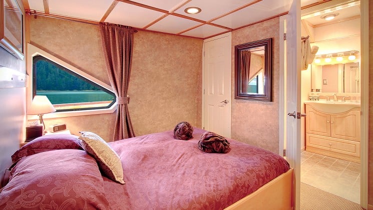 Pathfinder cabin with a large red bed and triangle window looking outside aboard the Safari Quest san juan islands small ship