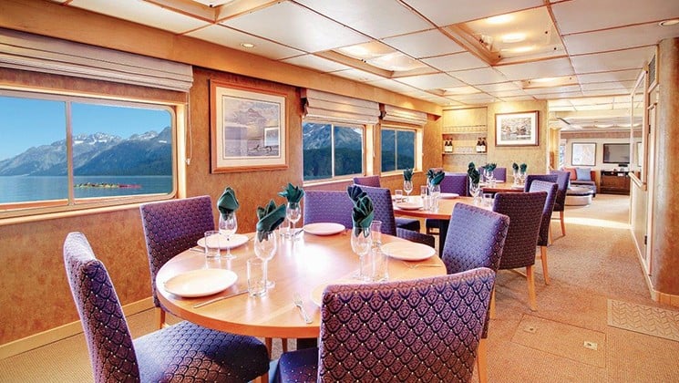 dining room with rows of tables and chairs, and rows of windows aboard the Safari Quest san juan islands small ship