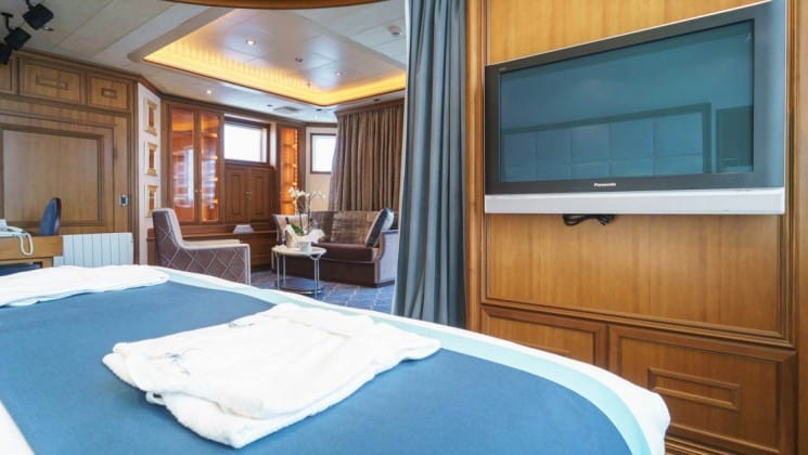 Large bed and TV with sitting area in background in Owner's Suite aboard Sea Spirit expedition ship