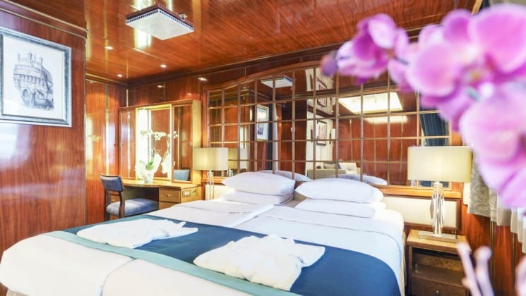 Large bed, two nightstands, desk and chair in Premium Suite aboard Sea Spirit expedition ship