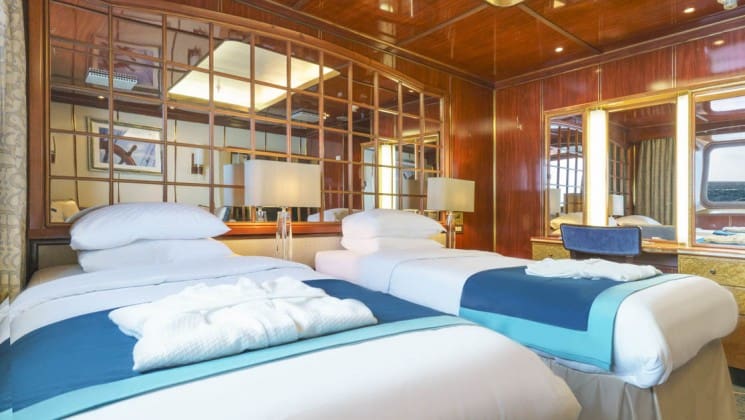 Two beds, desk, chair and large window in Superior Suite aboard Sea Spirit expedition ship