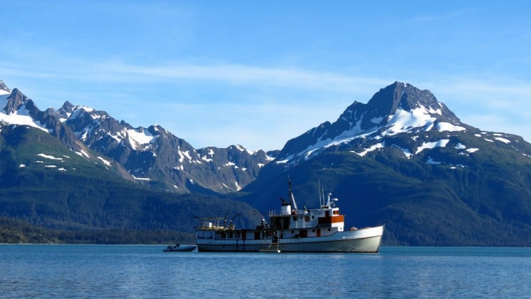 Full view of Sea Wolf yacht's starboard side with large Alaska mountains in background