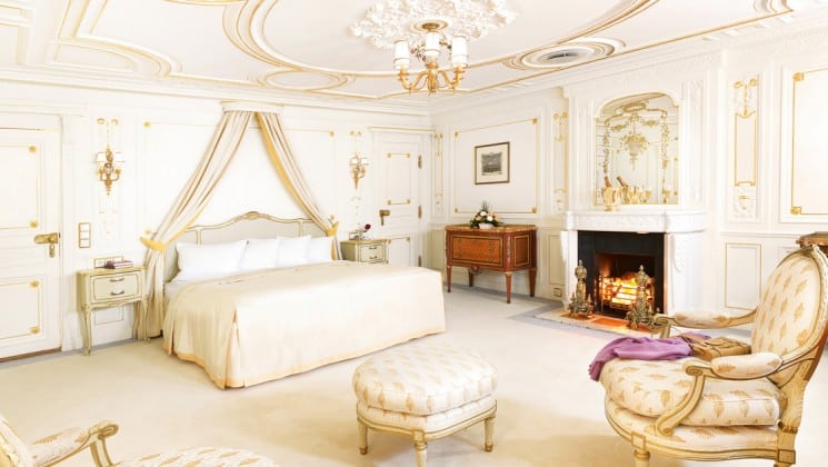all white room with a large bed, ottomans and fireplace aboard the Lindblad Sea Cloud mediterranean luxury yacht