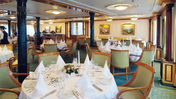 dining area with white tables, green chairs and pictures on the walls aboard the sea cloud ii mediterranean luxury yacht
