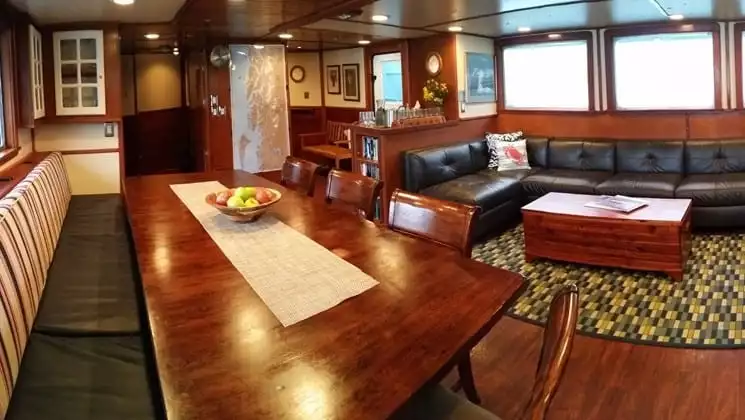Large couch and table with chairs in lounge aboard Sikumi small ship in Alaska