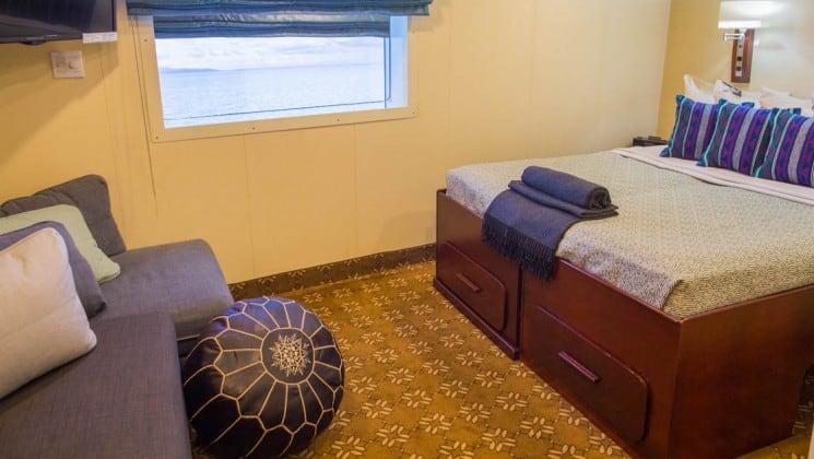 Safari Voyager Panama small ship jr commodore suite with large bed, comfortable chair and couch and large window