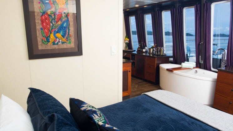 Safari Voyager Panama small ship Commodore suite with a large bed, opening to an adjoining room and large windows