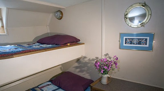 Discovery stateroom with upper and lower single berth and drawers and porthole.
