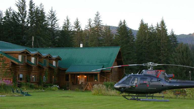A helicopter is parked on the lawn in front of the Bear Track Inn, a remote lodge ideal for accessing Glacier Bay, Alaska