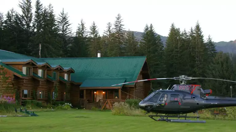 A helicopter is parked on the lawn in front of the Bear Track Inn, a remote lodge ideal for accessing Glacier Bay, Alaska