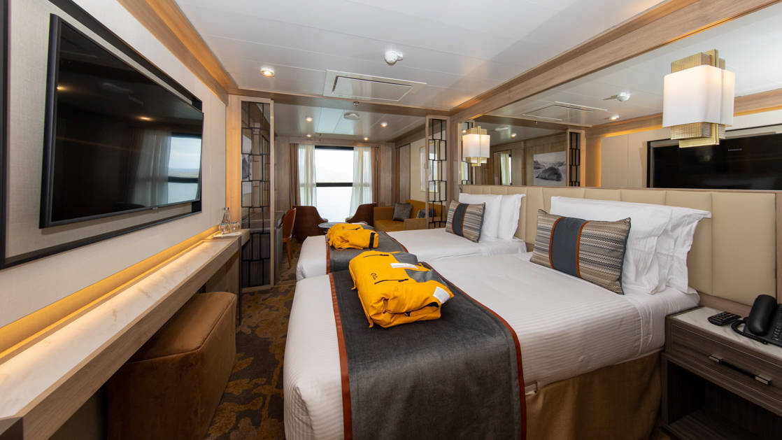Infinity Suite with 2 beds, 2 parks, TV and seating area aboard World Explorer polar small ship.