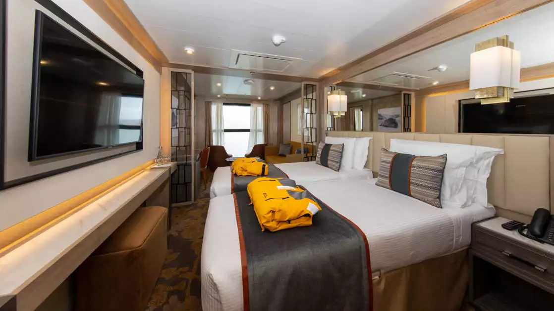 Infinity Suite with 2 beds, 2 parks, TV and seating area aboard World Explorer polar small ship.