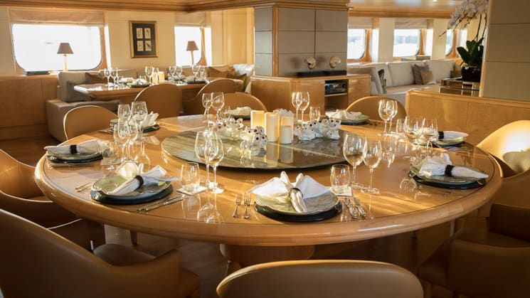 Dinning table aboard Indonesian yacht Aqua Blue, wooden table set with folded white napkins with tan leather chairs