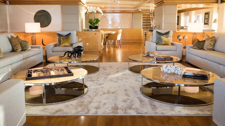 elegant wooden flooring with tan area rugs two circular couches around coffee tables aboard Indonesian yacht Aqua Blu