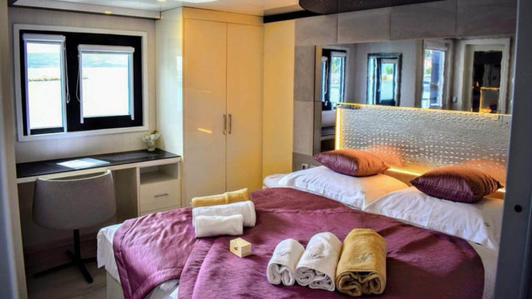 VIP Upper Deck cabin aboard Ave Maria with bed, wardrobe, and desk under window.