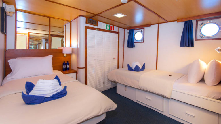 Cabin 2 aboard Beluga with two single beds and two portholes.