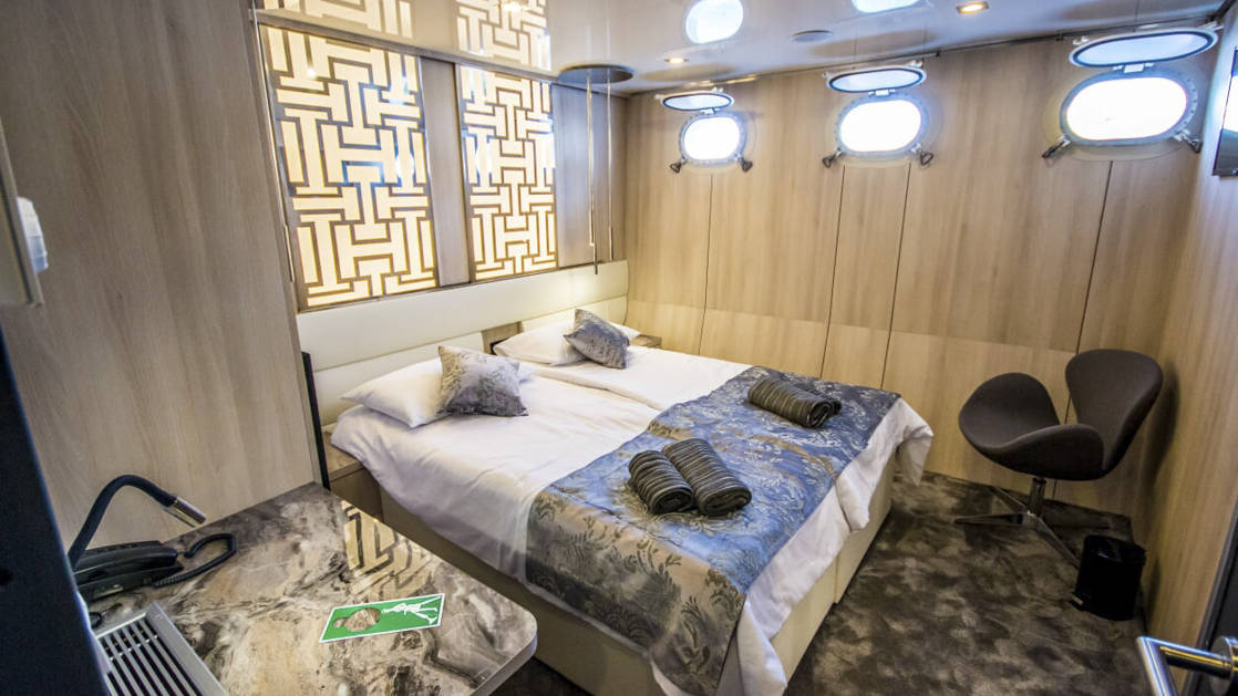 Lower Deck cabin aboard Black Swan with two beds together and three portholes.