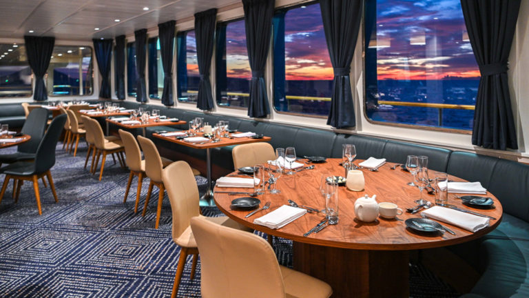 Empty dining room with set tables aboard Coral Adventurer.