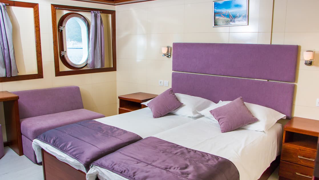 Futura Main deck cabin with double bed, nightstand, night light, window and seating.
